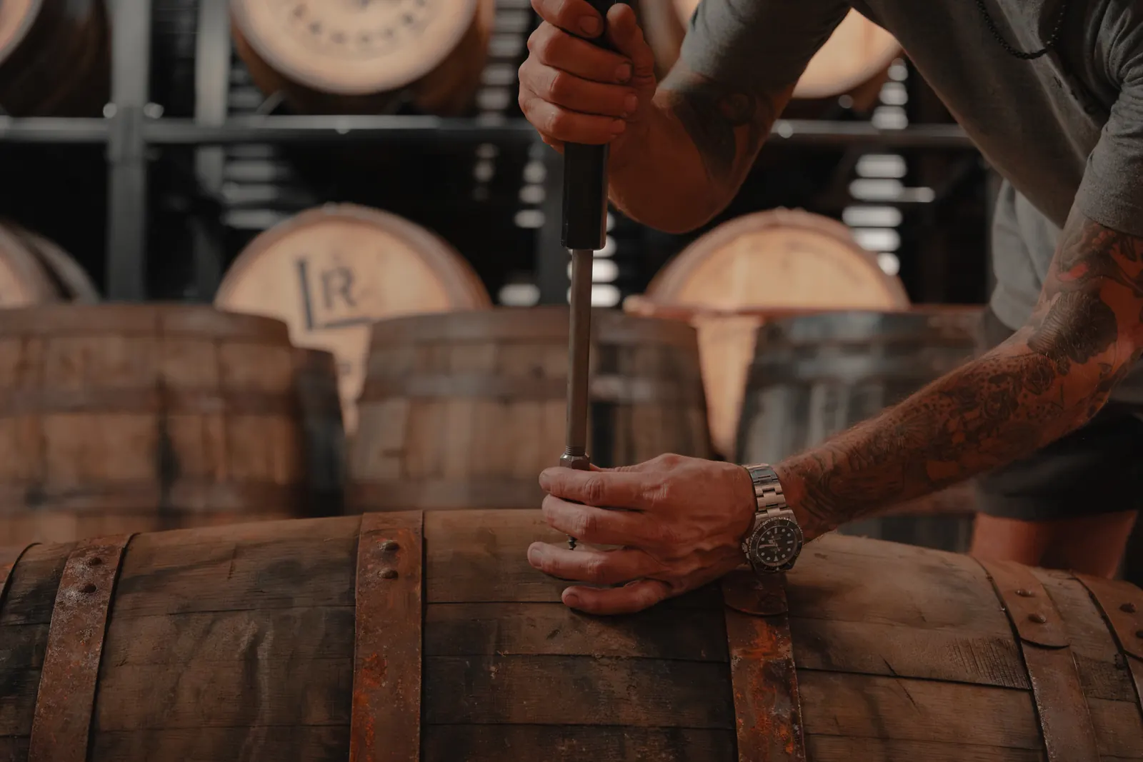 Tapping the bung on an aging whiskey barrel for a straight-from-the-barrel pour at Louisville Rickhouse